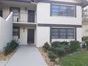 Condo exterior featuring front door entrance, balcony, clean walkway, and manicured landscaping at 5630 Golf Pointe Dr # 108, Sarasota, FL 34243