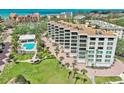 Beautiful condo building overlooking a sparkling pool, lush green lawn, and swaying palm trees at 8701 Midnight Pass Rd # 206A, Sarasota, FL 34242