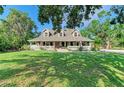 Traditional home with three dormers, covered porch, columns, and lush green lawn evokes Southern charm at 906 134Th E St, Bradenton, FL 34212