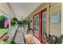 Inviting front porch with rocking chairs, hanging plants, and a red front door with decorative glass at 906 134Th E St, Bradenton, FL 34212