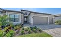 Exterior of gray home with stone veneer accents and a paved driveway, featuring a well-maintained lawn at 15332 Serene Shores Loop St, Bradenton, FL 34211