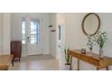 Bright foyer with white walls, tiled floor, a modern console table and coat rack at 15332 Serene Shores Loop St, Bradenton, FL 34211