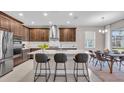 Modern kitchen with stainless steel appliances, a marble backsplash, an island with bar seating, and a dining table at 17502 Savory Mist Cir, Bradenton, FL 34211