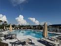 A serene community pool with ample seating and shade umbrellas overlooking a lake at 18044 Cherished Loop, Bradenton, FL 34211