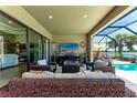 Relax on this covered lanai featuring comfortable seating, a TV, and a view of the pool at 19921 Petrino St, Venice, FL 34293