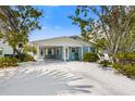 Charming blue beach house with white trim, a covered parking area, and lush tropical landscaping at 214 Palm Ave, Anna Maria, FL 34216