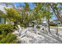 Outdoor seating area with chairs, a table, landscaping, and trees, perfect for relaxation at 214 Palm Ave, Anna Maria, FL 34216
