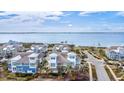 Waterfront real estate featuring colorful coastal homes with lush greenery, set against a backdrop of open water and blue skies at 319 Compass Point Dr # 201, Bradenton, FL 34209