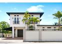 Stunning modern two-story home featuring a white exterior, black trim, and lush tropical landscaping at 324 Siesta Dr, Sarasota, FL 34242