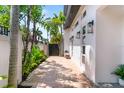Charming exterior with mature landscaping, brick driveway, outdoor seating, and modern architectural details at 324 Siesta Dr, Sarasota, FL 34242