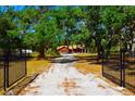 Wide angle view of a gravel driveway, mature trees, and gated entrance at 3406 67Th Street E Ct, Bradenton, FL 34208