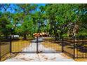 Gated entrance to a property with mature trees and a gravel drive at 3406 67Th Street E Ct, Bradenton, FL 34208