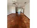 Open-concept living room with terracotta tile flooring, ceiling fans, and ample natural light at 3705 Chinaberry Rd, Bradenton, FL 34208