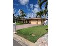 Beautiful single-story house featuring a three-car garage, brick driveway, lush lawn, and tropical palm trees at 3716 Coconut Ter, Bradenton, FL 34210