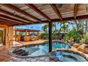 An inviting backyard featuring a covered patio, custom pool and spa, and tropical landscaping, ideal for relaxation at 3716 Coconut Ter, Bradenton, FL 34210