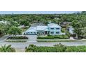 Aerial view of a two-story home with a metal roof surrounded by lush greenery and a paver driveway at 4153 Camino Real, Sarasota, FL 34231