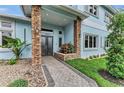 Elegant entryway featuring stone columns, double doors, a paver walkway, and lush landscaping at 4153 Camino Real, Sarasota, FL 34231
