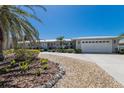 Charming one-story home featuring an attached garage, unique front door, and tropical landscaping at 606 Emerald Ln, Holmes Beach, FL 34217