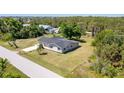 A charming single story home featuring a gray roof and a well-maintained lawn with lush greenery at 8308 Pelican Rd, Englewood, FL 34224