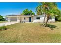 A charming home with a well-manicured lawn, a gray garage door, and a vibrant palm tree in the front yard at 8308 Pelican Rd, Englewood, FL 34224