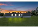 Exterior shot of home with lights on, showcasing its charming curb appeal against a beautiful sunset at 8414 Sweden Blvd, Punta Gorda, FL 33982