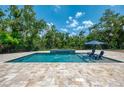 Beautiful outdoor pool and spa area with travertine tile and lush landscaping at 95 Vic Edwards Rd, Sarasota, FL 34240