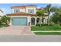Charming home featuring a brick driveway, aqua garage door and shutters, red tile roof, and lovely landscaping at 13721 Saw Palm Creek Trl, Lakewood Ranch, FL 34211