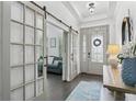 Inviting foyer with wood floors, glass French doors, modern lighting, and an elegantly decorated front door at 13721 Saw Palm Creek Trl, Lakewood Ranch, FL 34211