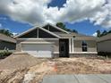 Charming one-story home with a two-car garage and stone accents, set against a bright blue sky with scattered clouds at 19575 Fort King Run, Brooksville, FL 34601