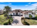 Charming single-Gathering home featuring a well-manicured lawn, brick driveway, and beautiful landscaping at 26725 Raphis Royale Blvd, Englewood, FL 34223