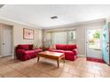 Inviting living room featuring tile floors, a front door, and comfortable red sofas at 337 Somerset Ave, Sarasota, FL 34243