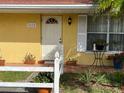 Inviting front porch with vibrant flowers and plants, stylish light fixture, and a white door with decorative window at 3612 27Th W Ave, Bradenton, FL 34205