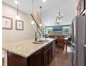 An open kitchen with stainless appliances and a large island adjacent to a dining and living area at 3623 Pitch Ln, Sarasota, FL 34232