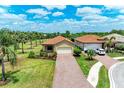 An elevated front view of a house with lush landscaping, brick driveway, and a spacious two-car garage at 10111 Malachite Dr, Bradenton, FL 34211