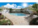 Inviting community pool surrounded by lounge chairs, tropical landscaping, and charming two-story buildings at 1020 Sun N Sea Dr # 104B, Sarasota, FL 34242