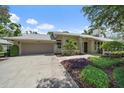 Charming home featuring a lush, well-manicured front yard, landscaping, and an attached garage at 1046 Greystone Ln, Sarasota, FL 34232