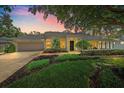 Charming home featuring a lush, well-manicured front yard and landscaping at dusk at 1046 Greystone Ln, Sarasota, FL 34232