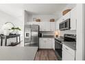 Modern kitchen boasts stainless steel appliances, white cabinetry, and sleek countertops at 1800 Little Bird Ct, Sarasota, FL 34235