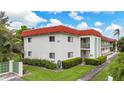 Low angle of a two-story condo complex with a red roof and lush, green landscaping on a bright, sunny day at 3500 Beneva Rd # 306, Sarasota, FL 34232