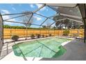 A screened-in pool is surrounded by a wooden fence and lush landscaping at 3600 Aster Dr, Sarasota, FL 34233