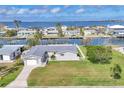 Charming waterfront home featuring a lush green lawn, well-maintained landscaping, and access to the beautiful blue waters beyond at 4911 Commonwealth Rd, Palmetto, FL 34221