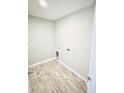 Compact laundry room with modern light wood flooring and essential hookups for a washer and dryer at 5113 Rilke Ln, Port Charlotte, FL 33981