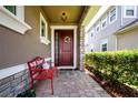 Inviting front entry with a red door and a decorative wreath, bench seating and brick pathway at 5252 Bentgrass Way, Bradenton, FL 34211