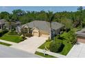 An exterior view showcases a single-story home with tropical landscaping and a driveway leading to a two-car garage at 5603 90Th Avenue E Cir, Parrish, FL 34219
