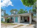 Single-story home with a covered parking area, tidy landscaping, and a brightly colored teal entry door at 5732 Beneva Rd, Sarasota, FL 34233