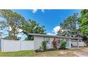 Inviting single-story home with a well-kept lawn, complemented by a white fence and mature trees at 5732 Beneva Rd, Sarasota, FL 34233