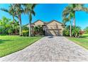 Charming home featuring a paver driveway, lush landscaping, and mature palm trees in a well-maintained front yard at 618 148Th Ne Ct, Bradenton, FL 34212