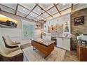 Spacious home office with a tray ceiling, brick accent wall and wooden desk at 6600 Horned Owl Pl, Sarasota, FL 34241