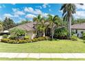 Landscaped front yard with palm trees enhancing this beautiful home, complete with a well-maintained lawn at 7913 Osprey Hammock Ct, Sarasota, FL 34240