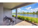 Covered patio with brick flooring features rocking chairs and serene views of the lake and landscaping at 10217 Canaveral Cir, Sarasota, FL 34241